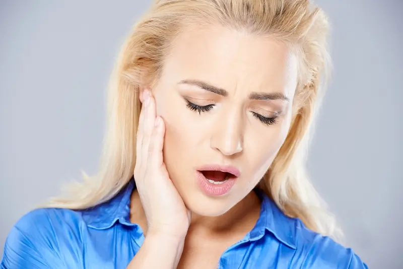 Woman holding jaw in pain. 